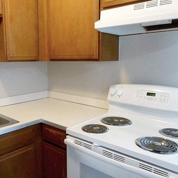 a white stove is in a kitchen with wooden cabinets.