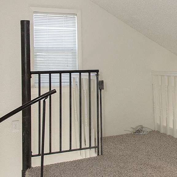 a room with a carpeted floor and a staircase with a black railing.