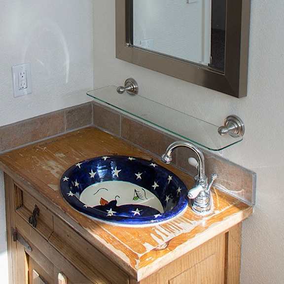 a blue and white bowl with a cat and butterfly design sits on a wooden countertop.