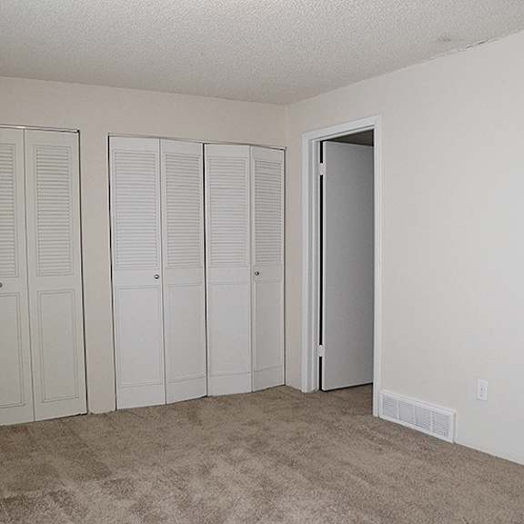 closet with white doors and carpeted floor.