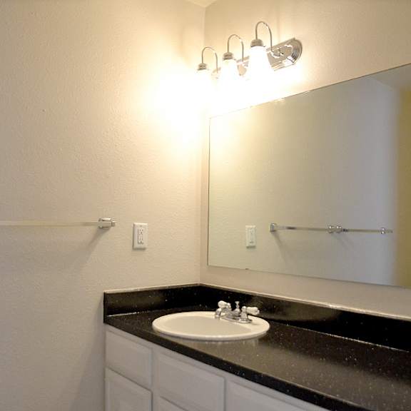a bathroom with a sink, mirror, and lights.