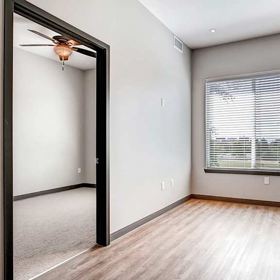 a room with a ceiling fan and a window with blinds.