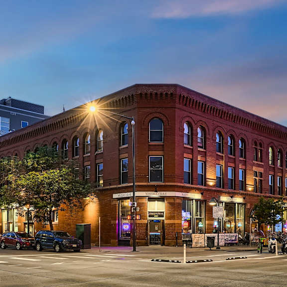 a red brick building with a lit up window on the corner.