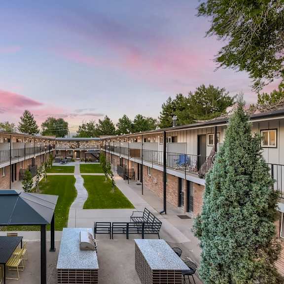 a sunset view of a courtyard with a picnic table and chairs.