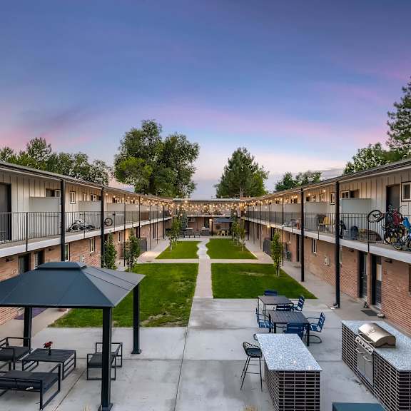 a patio area with a table and chairs is surrounded by apartment buildings.