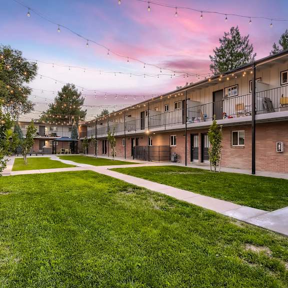 a sunset view of a residential area with apartment buildings and green lawns.