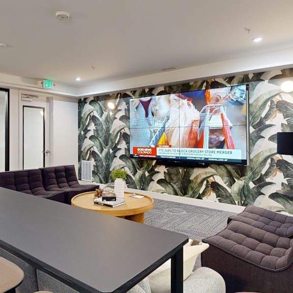 a conference room with a long table and chairs, a television on the wall, and a carpeted area with a couch.