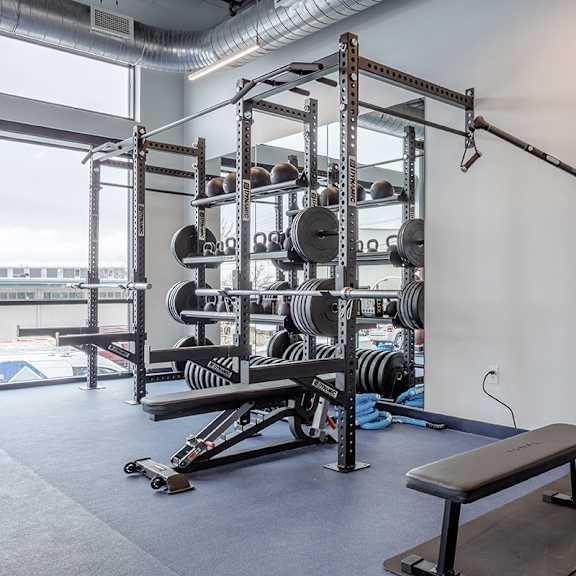 a gym with a bench, weights, and mirrors.