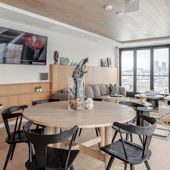 a modern living room with a large wooden table surrounded by chairs.
