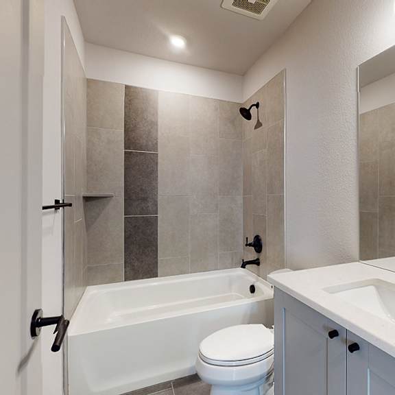 a bathroom with a white tub, sink, and toilet.