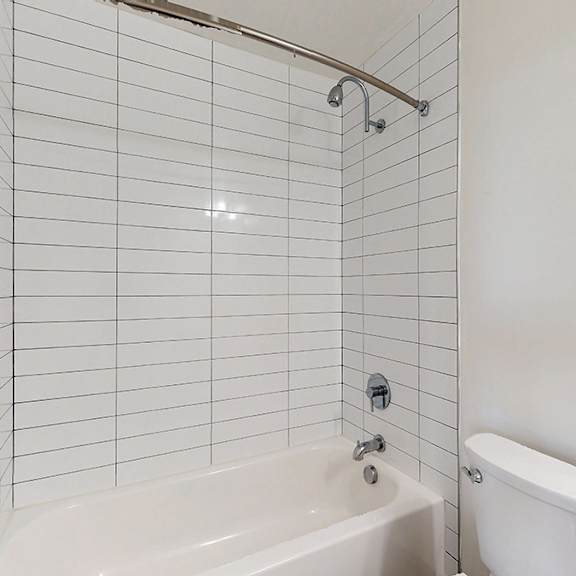 a white bathroom with a tub, toilet, and shower.