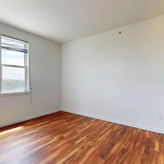 a room with wooden floors and two windows.