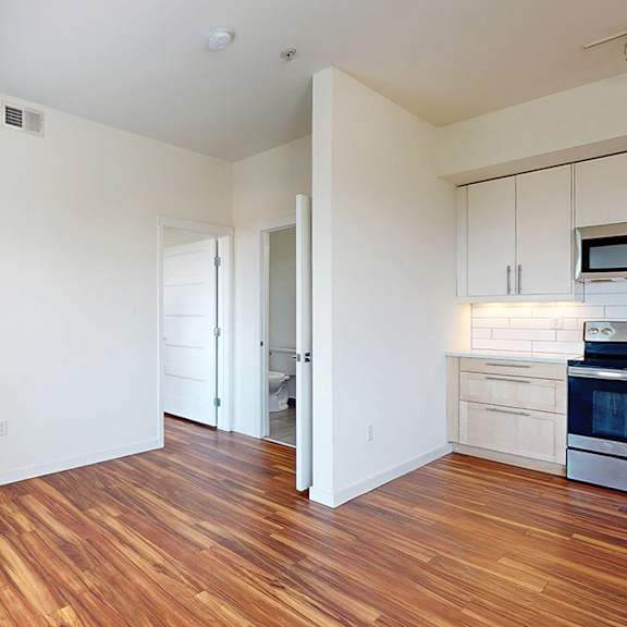 a kitchen with white cabinets and a wooden floor.