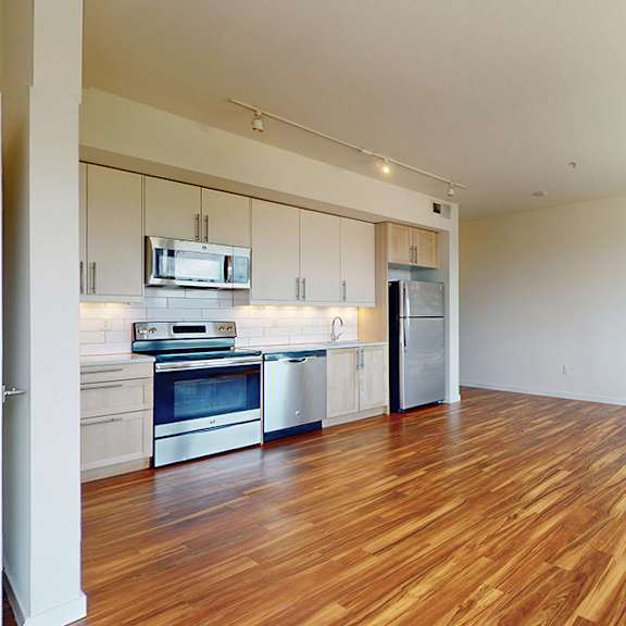 a kitchen with wooden floors and stainless steel appliances.