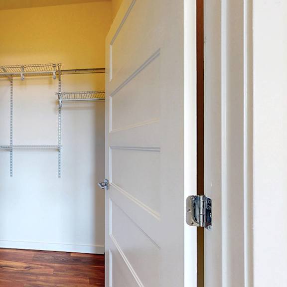 a white door is open to a hallway with a white wall and a wooden floor.
