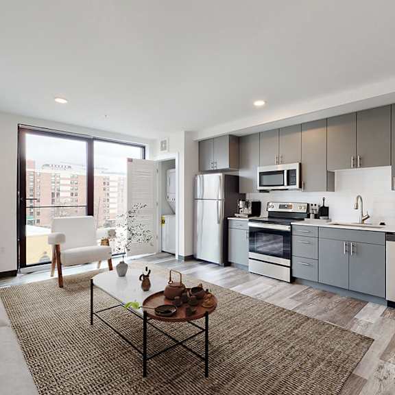 a modern kitchen and living room with a grey sofa and a coffee table.
