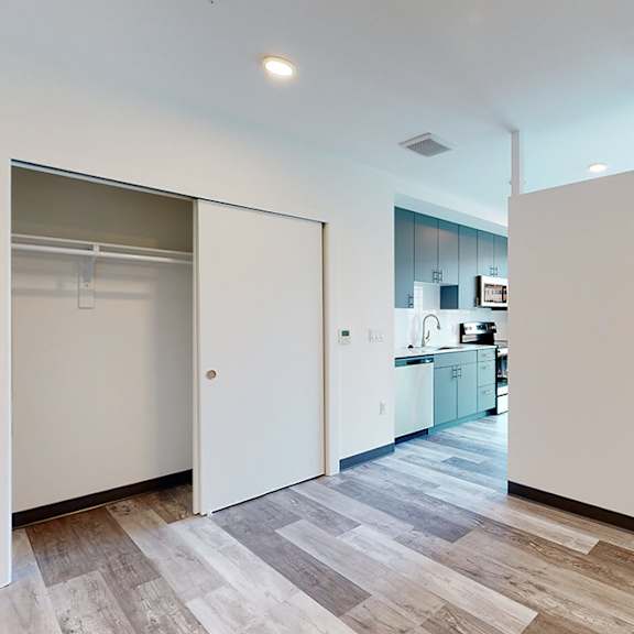 a kitchen area with a white wall and a wooden floor.