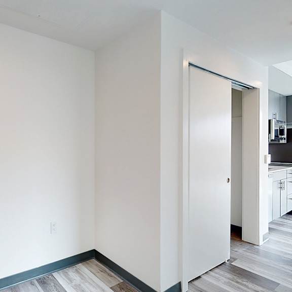 a white room with a door and a wooden floor.