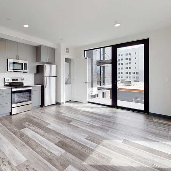 a modern kitchen with wooden flooring and stainless steel appliances.