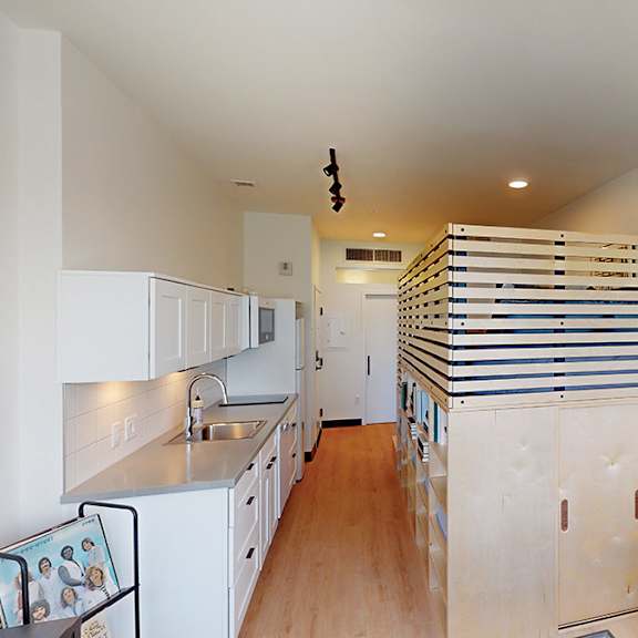 a kitchen with white cabinets and a wooden floor.