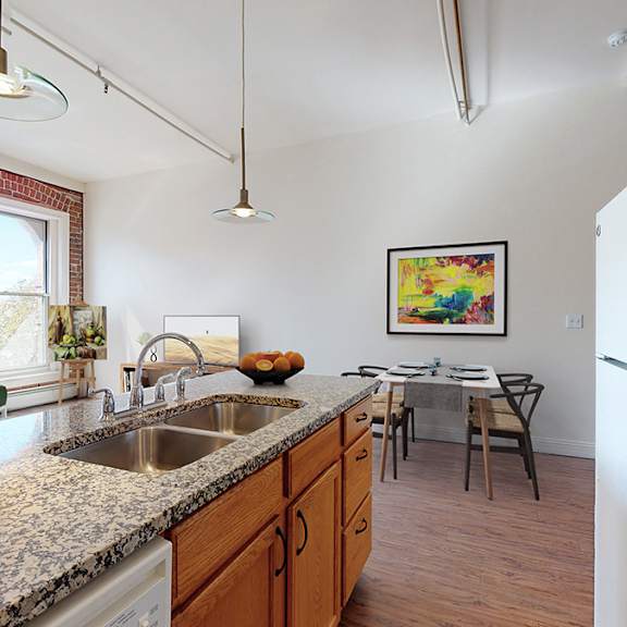 a kitchen with a refrigerator, sink, and a dining table with chairs.