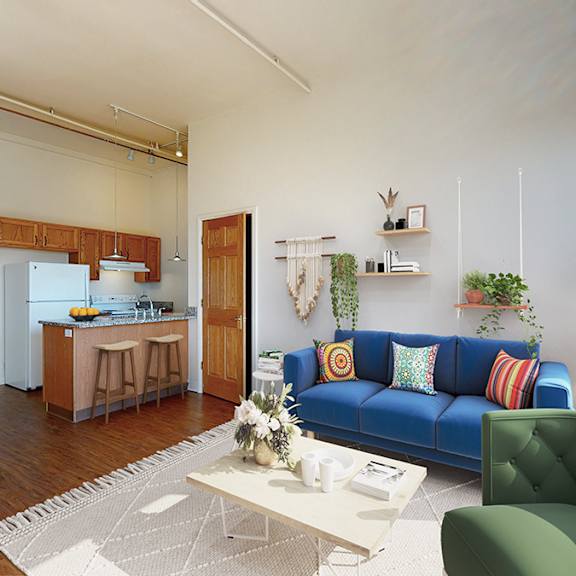 a open-plan living room with a blue couch and a coffee table, with kitchen in the background.