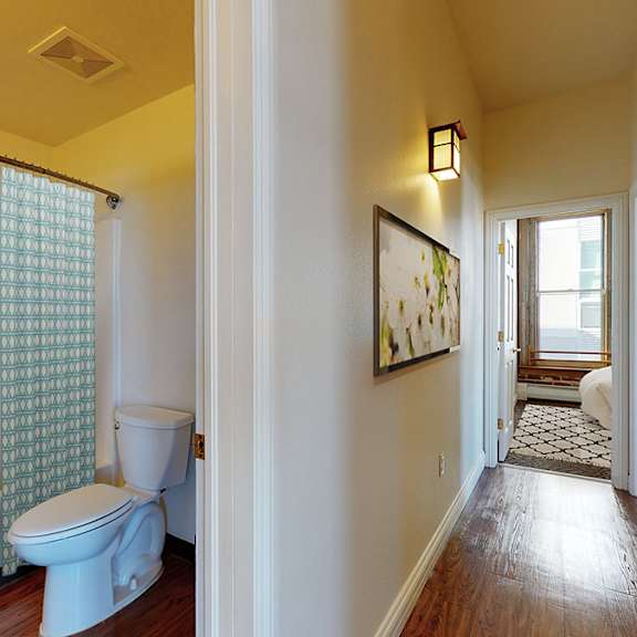 a bathroom with a toilet, a bathtub, and a window with a curtain.