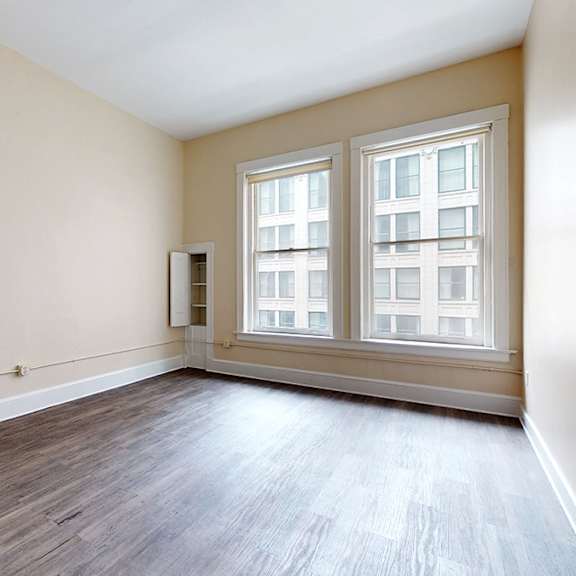 a room with wooden floors and two windows.