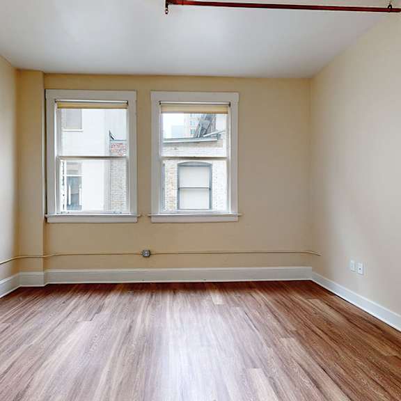a room with wooden floors and two windows.