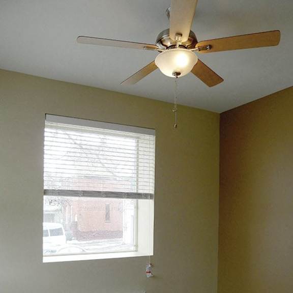 a room with a ceiling fan, window with blinds, and an air conditioner.