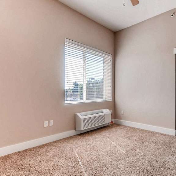 a room with a window, a carpet, and a white door.