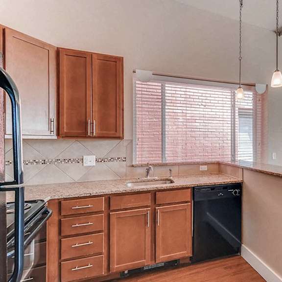 a kitchen with wooden cabinets and a black dishwasher.