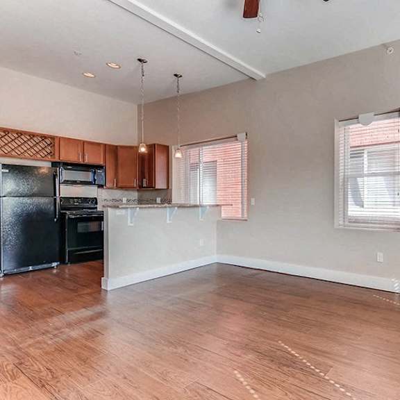 a kitchen with wooden floors and a black refrigerator.