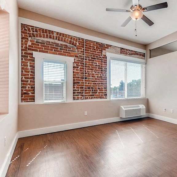 a room with a brick wall and a ceiling fan.