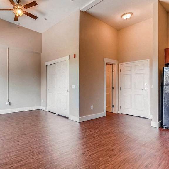 a room with a ceiling fan and wooden floors.