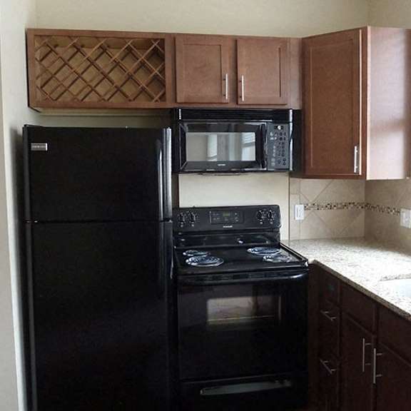 a black refrigerator and oven in a kitchen.