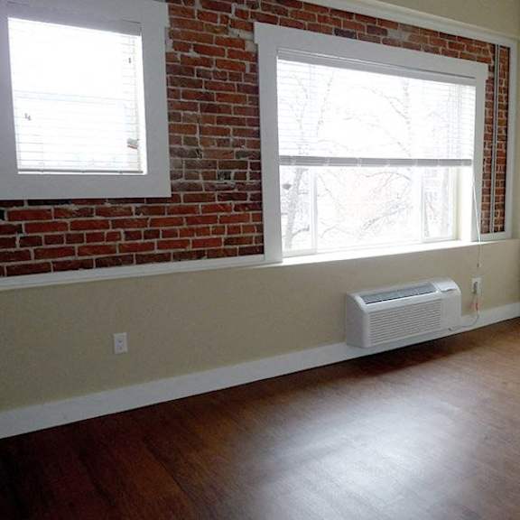 a room with a red brick wall and a window with blinds.