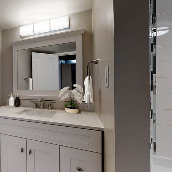 a bathroom with a white vanity and a painting of flowers on the wall.