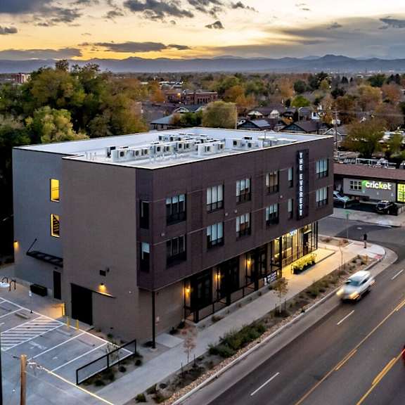 a modern building is situated on a busy street with cars driving by.