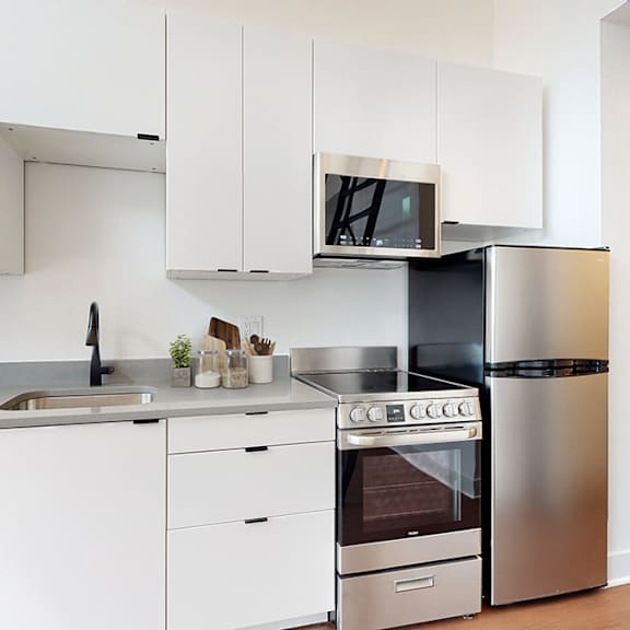 a modern kitchen with stainless steel appliances and white cabinets.
