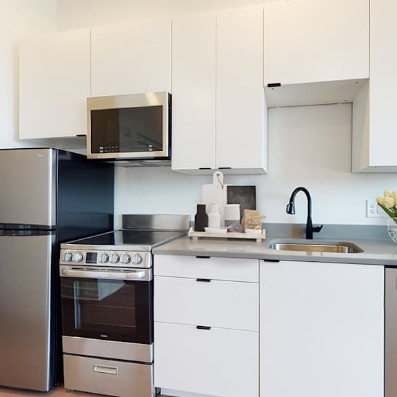 a modern kitchen with stainless steel appliances and white cabinets.