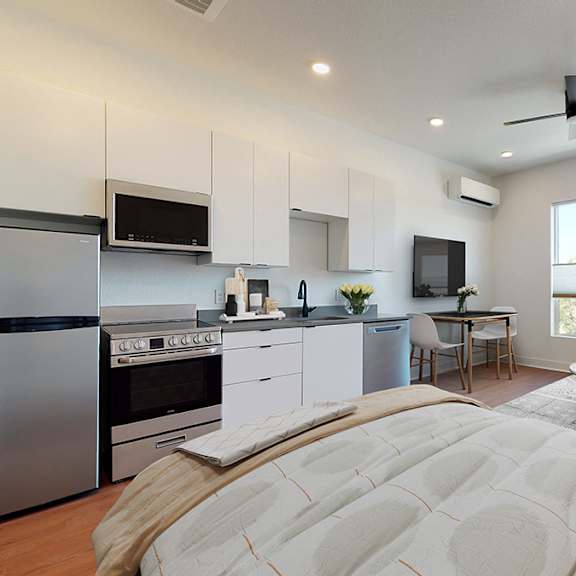 a modern kitchen with stainless steel appliances and a large bed in the foreground.