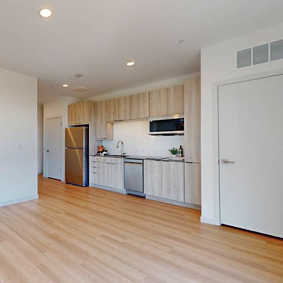 a kitchen with a white fridge and wooden floors.