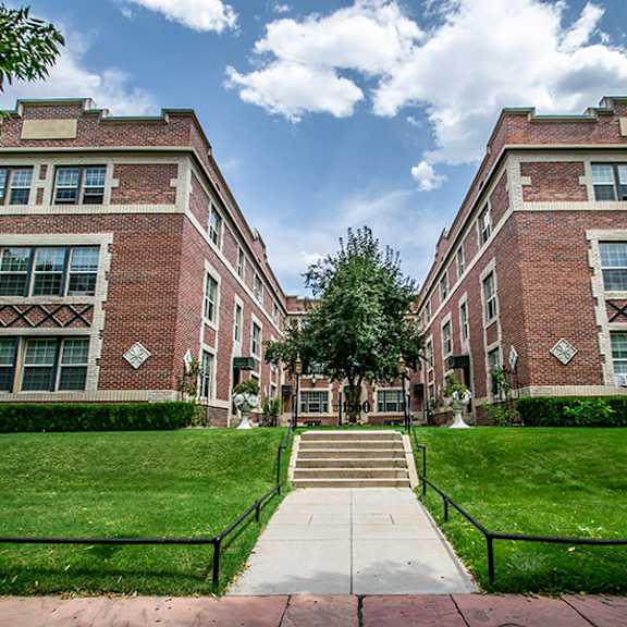 a large brick building with a green lawn in front.