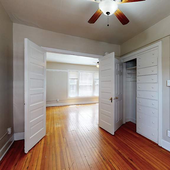 a room with a ceiling fan and wooden floors.