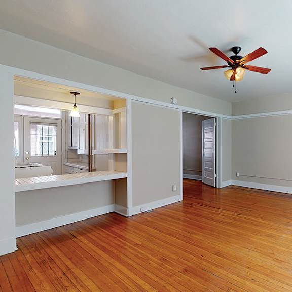 a room with a ceiling fan and hardwood floors.