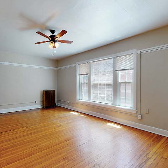 a room with a ceiling fan and wooden floors.