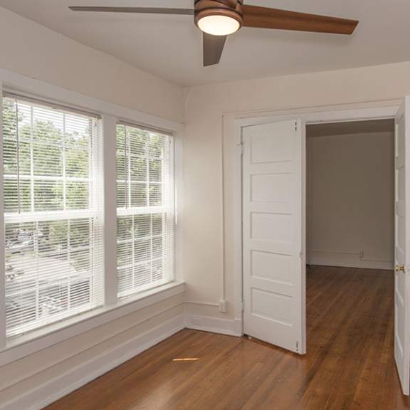 a room with a ceiling fan and a door leading to another room.