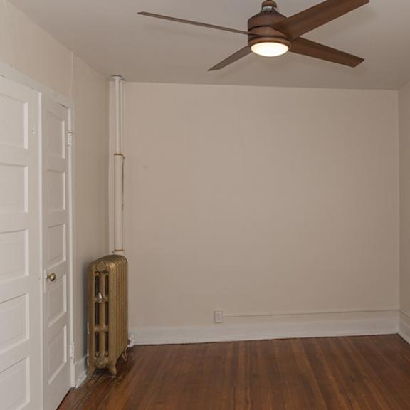 a room with a ceiling fan and a radiator on the floor.