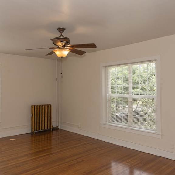 a room with a ceiling fan and two windows.